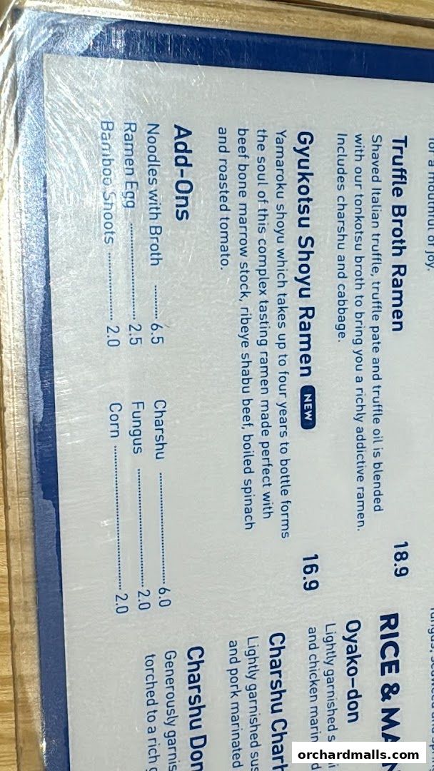 A close-up of a ramen menu with various ramen dishes and add-ons listed.