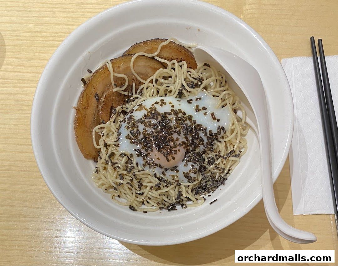 A bowl of ramen with chashu pork, a soft-boiled egg, and seaweed.