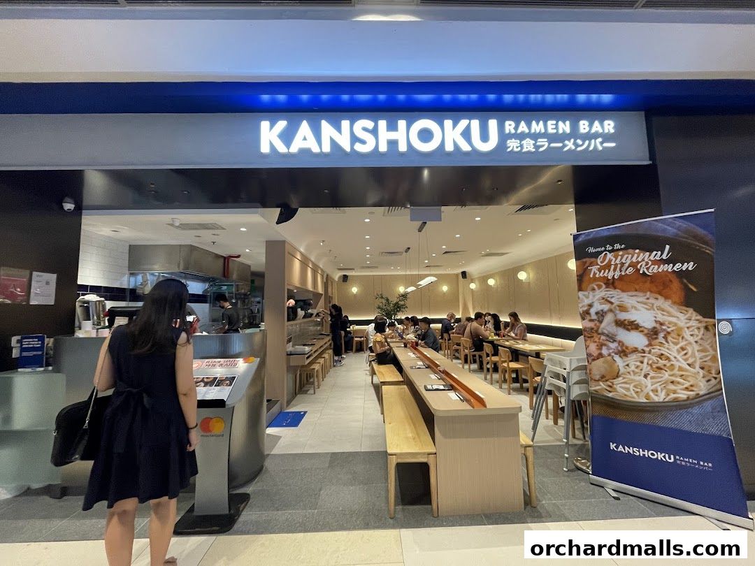 The entrance of Kanshoku Ramen Bar with customers dining inside and a banner advertising truffle ramen.