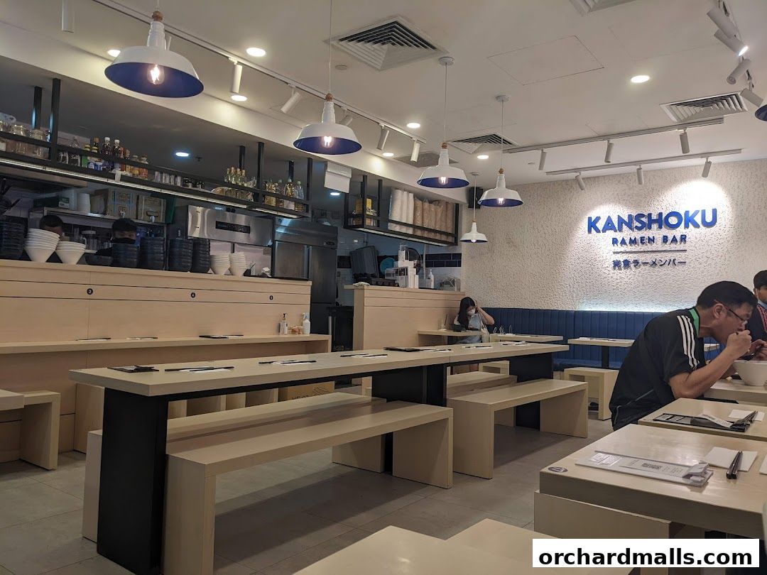 Interior of Kanshoku Ramen Bar with modern seating and a view of the kitchen.