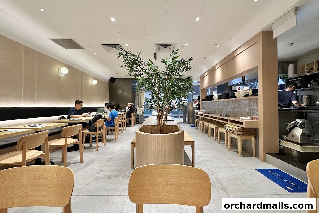 Interior of Kanshoku Ramen Bar with diners seated at tables and a central tree.