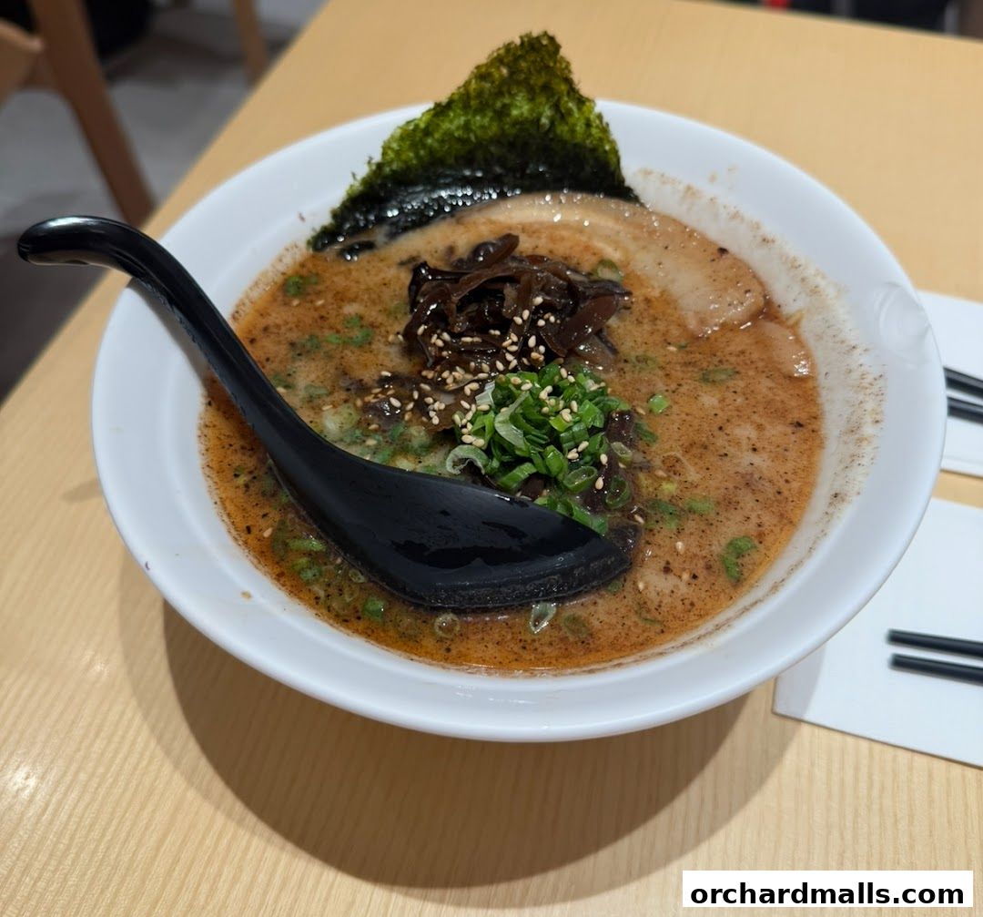 A steaming bowl of rich ramen with pork, seaweed, and green onions.