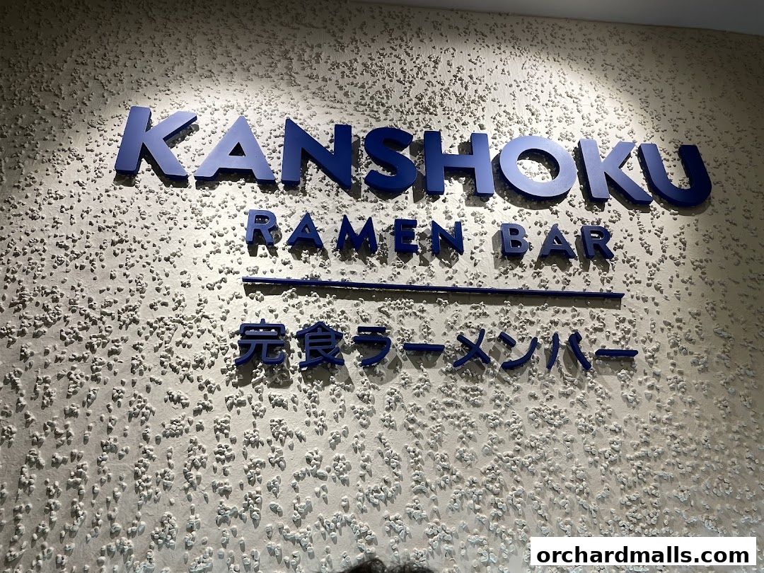 The Kanshoku Ramen Bar sign with blue lettering on a textured wall.