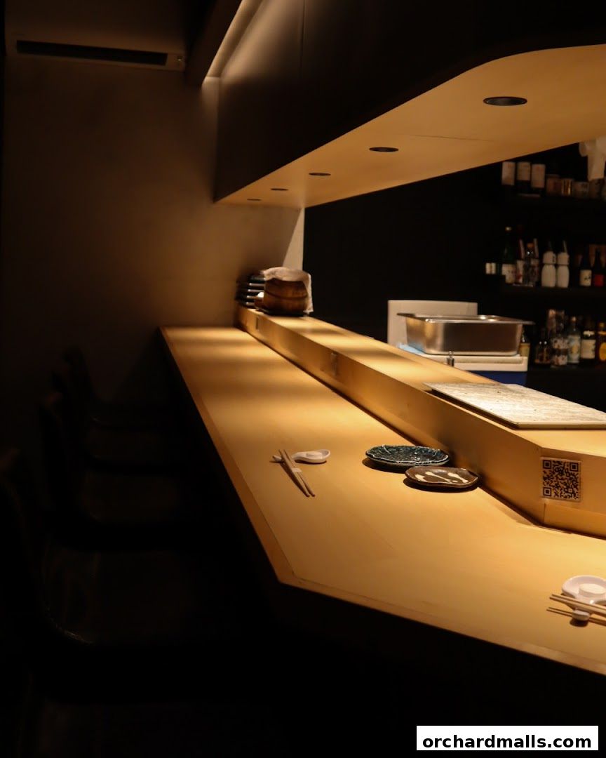 A clean and modern sushi bar counter with chopsticks and plates set for dining.