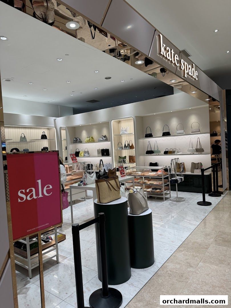 Kate Spade New York store interior with handbags displayed and a sale sign.