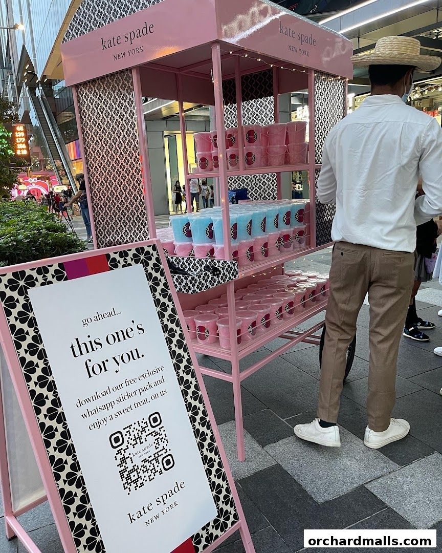 A Kate Spade New York cart offering sweet treats and a QR code for a sticker pack.