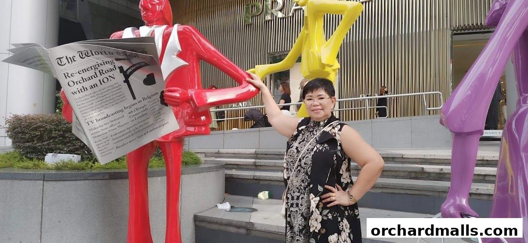 A woman poses with colorful statues in front of a Prada store.