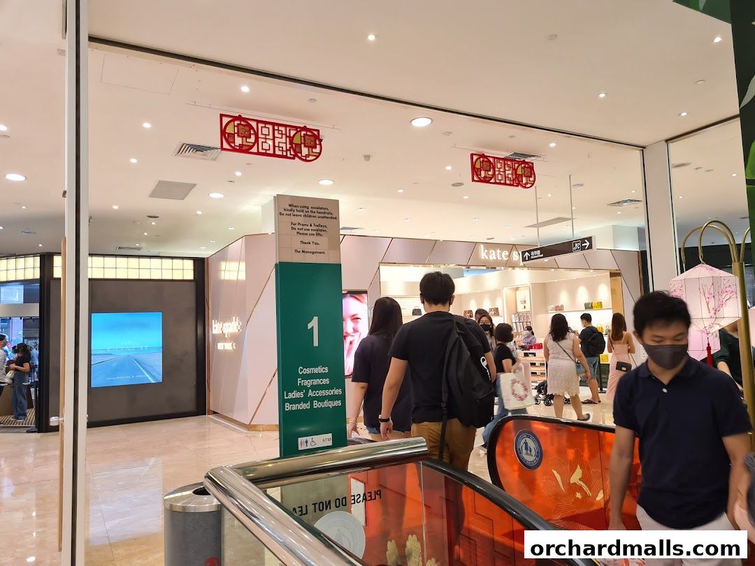 People walking past a Kate Spade New York store entrance in a shopping mall.