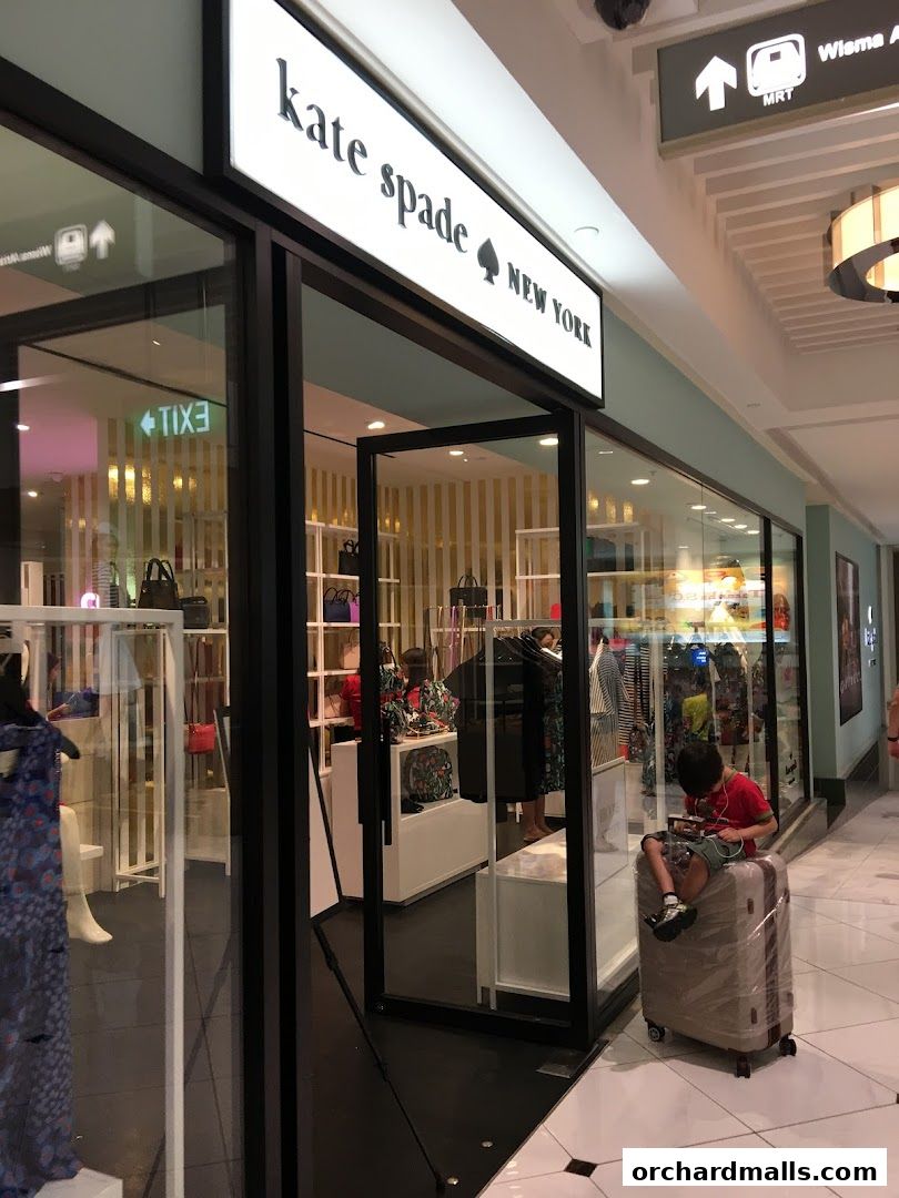 Kate Spade New York store entrance with handbags and clothing displayed inside.