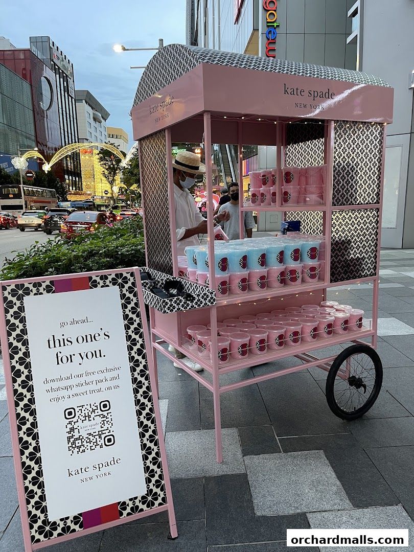 Kate Spade New York promotional cart offering sweet treats and a QR code for a sticker pack.