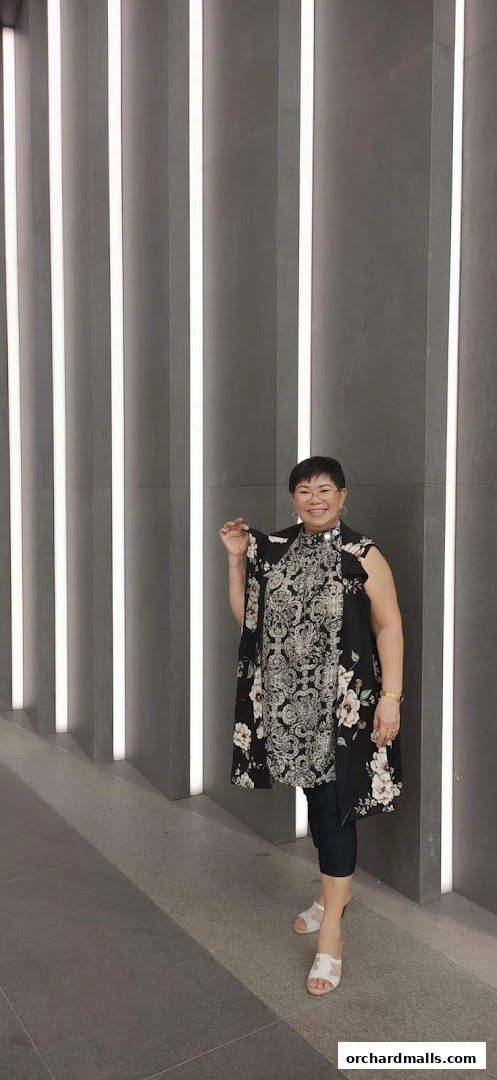 A woman poses in front of a modern wall with vertical lighting.
