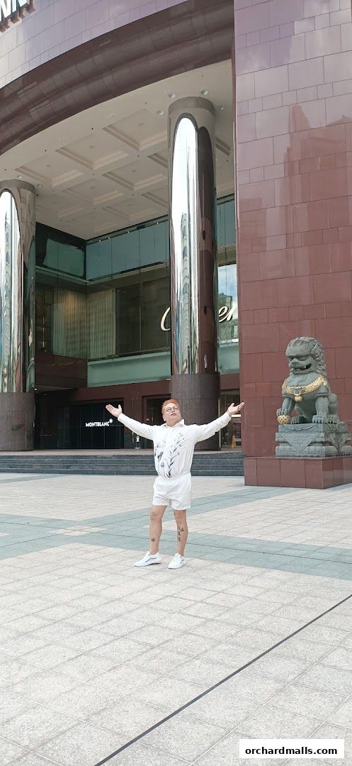A person stands with arms outstretched in front of the Montblanc store entrance.