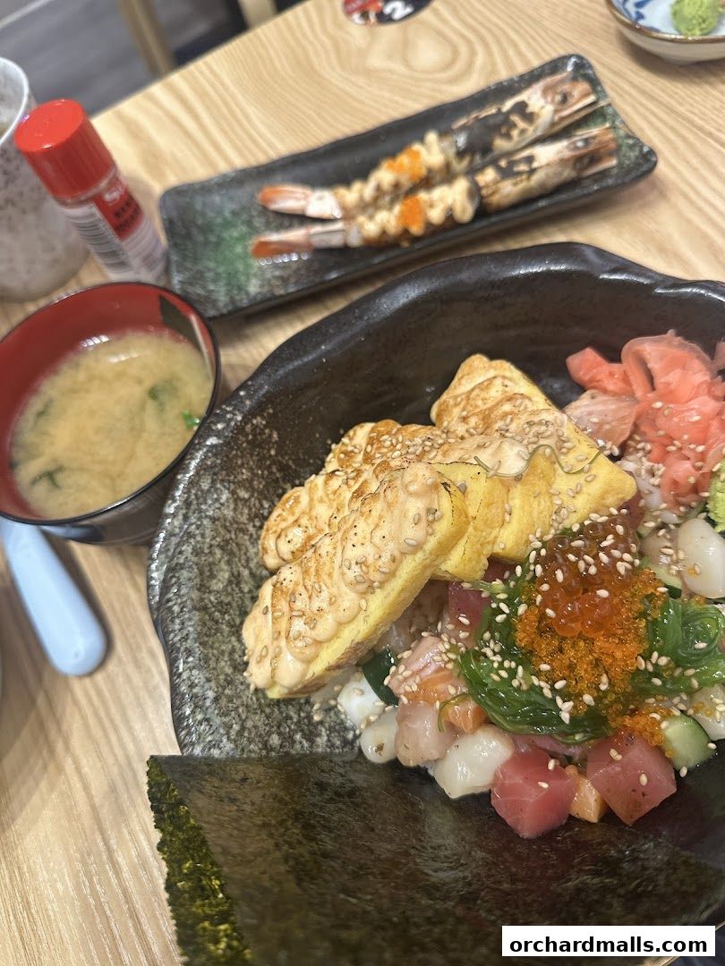 A close-up of a delicious Kaisendon bowl with grilled shrimp and miso soup.