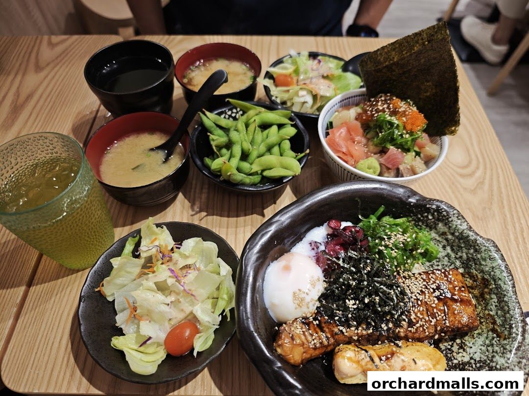 A table laden with Japanese dishes including Kaisendon, miso soup, salad, and edamame.