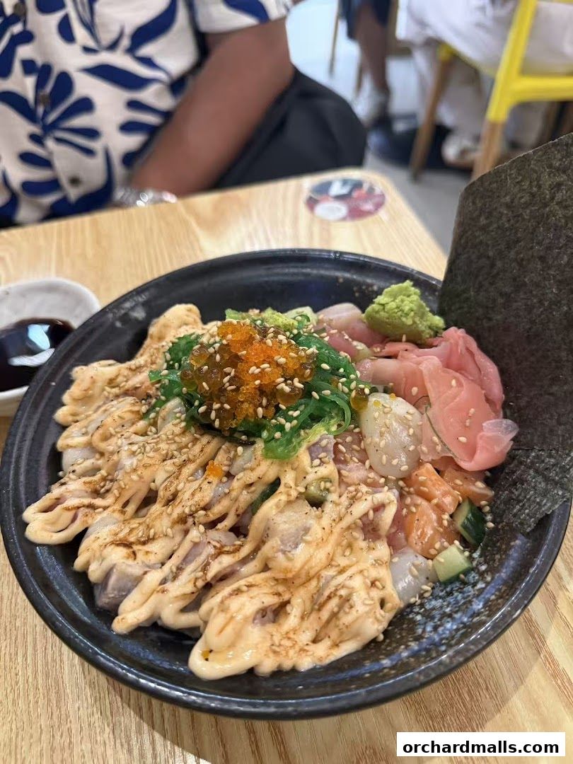 A close-up of a delicious Kaisendon bowl with fresh sashimi, seaweed salad, and sauce.