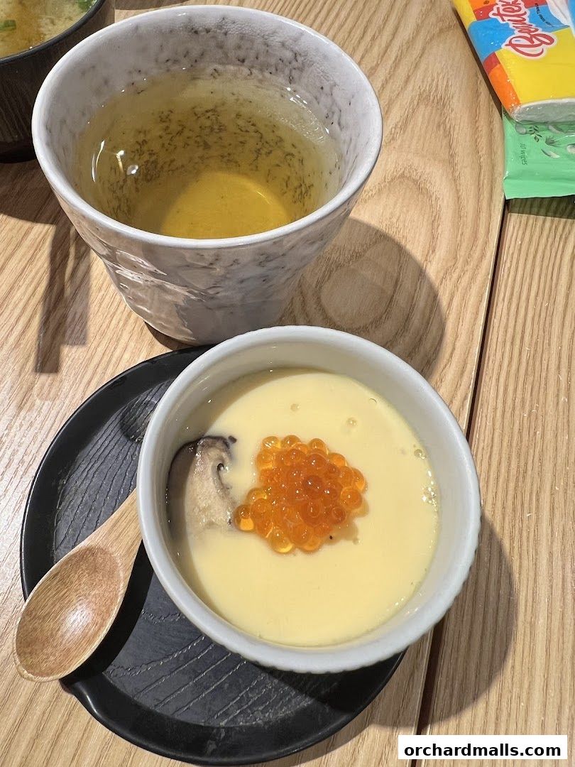A close-up of Japanese chawanmushi with ikura and shiitake mushroom, served with tea.