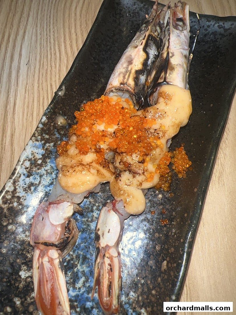 A close-up of a seafood dish featuring large prawns topped with roe and sauce.