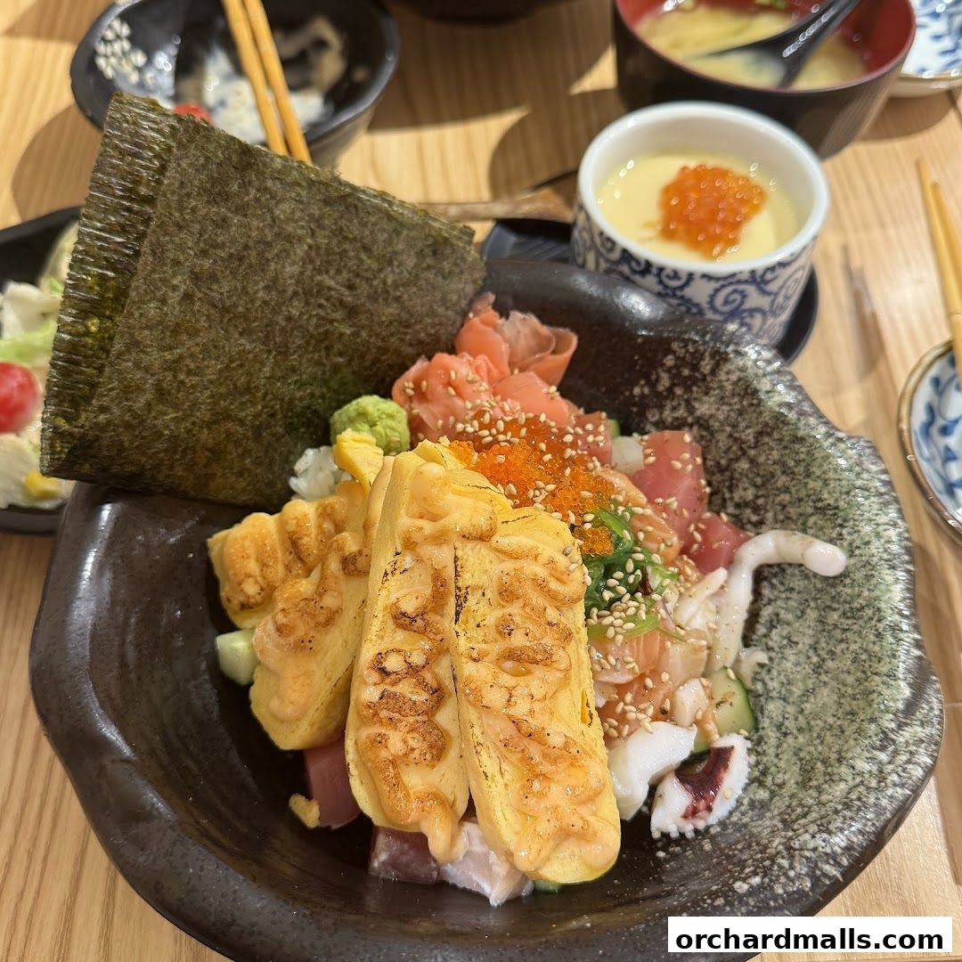 A close-up of a delicious Kaisendon bowl with fresh sashimi, tamagoyaki, and seaweed.