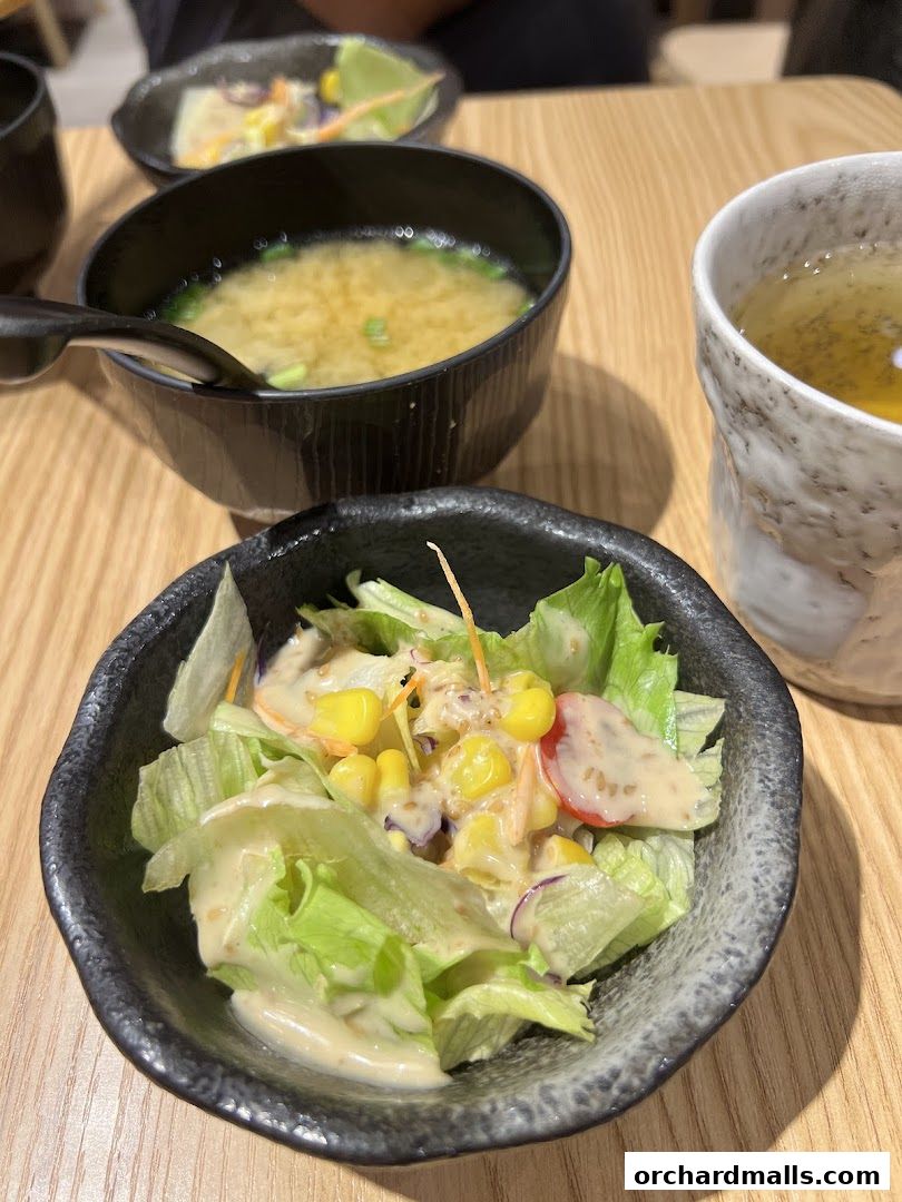 A close-up of a salad and miso soup with a cup of tea on a wooden table.