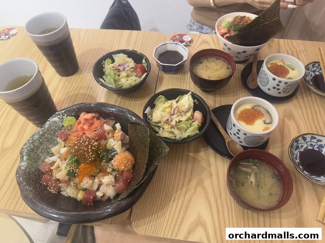 A table laden with Japanese dishes including Kaisendon, chawanmushi, miso soup, and salad.