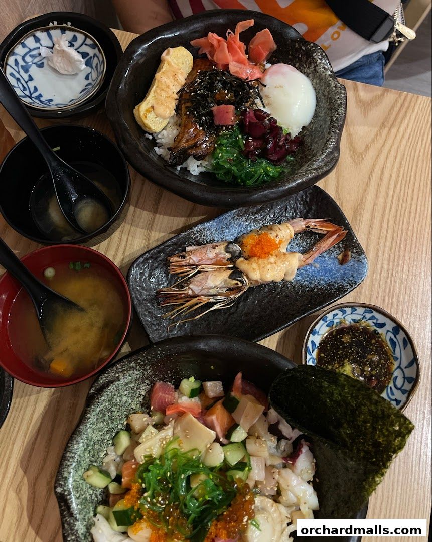 A top-down view of several Japanese dishes, including Kaisendon and grilled prawns.