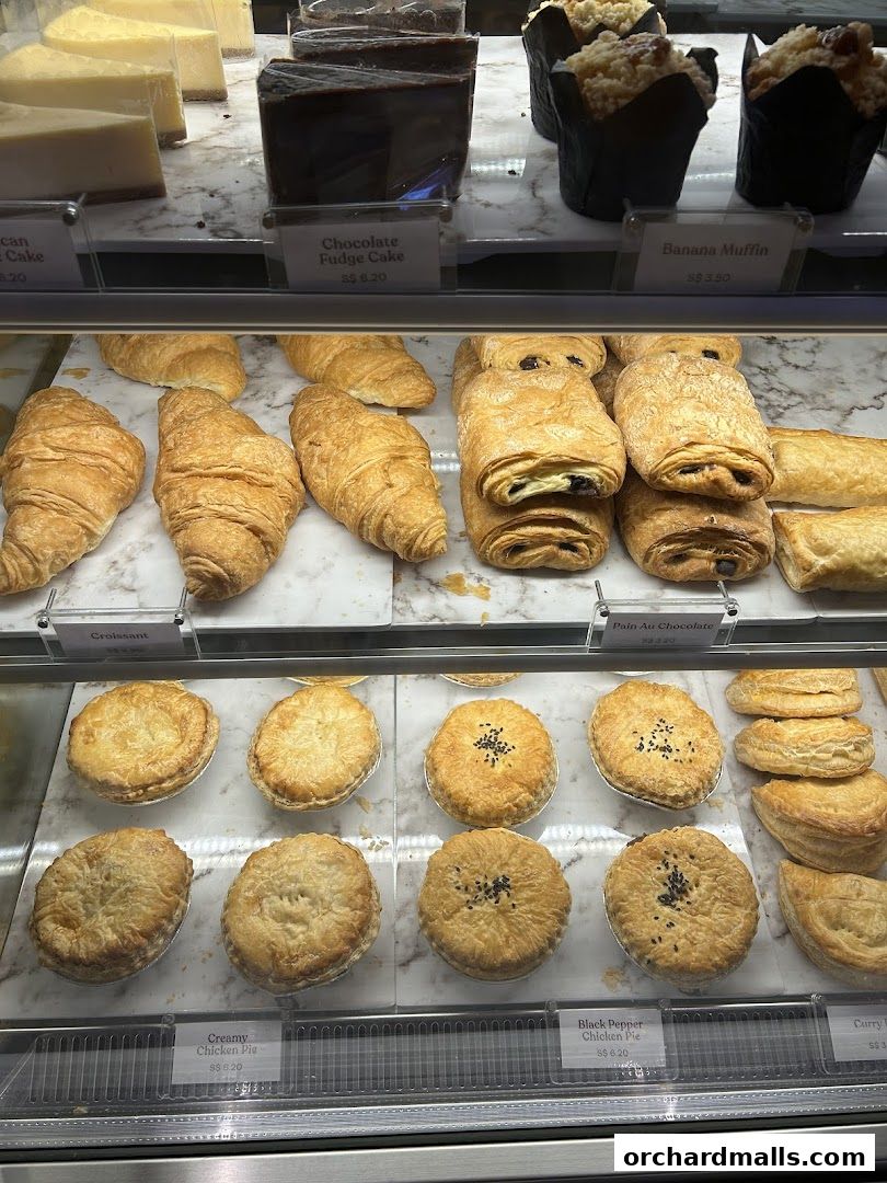 A display case filled with various pastries, cakes, muffins, and pies.