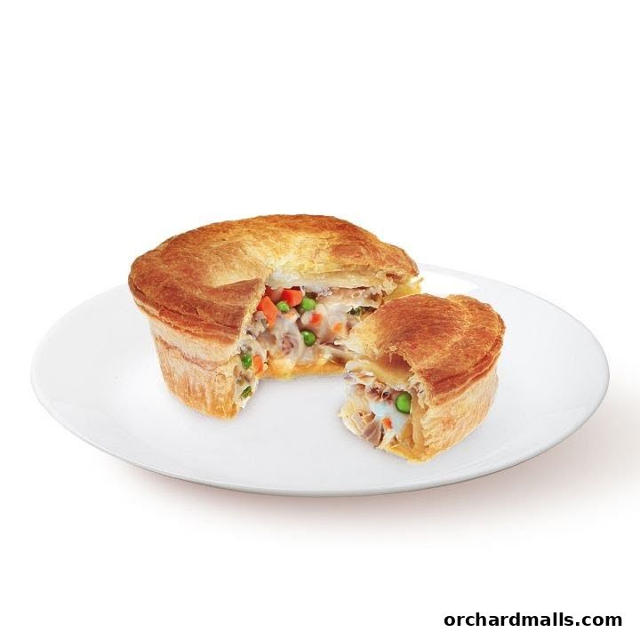 A savory pie filled with chicken and vegetables, cut in half on a white plate.
