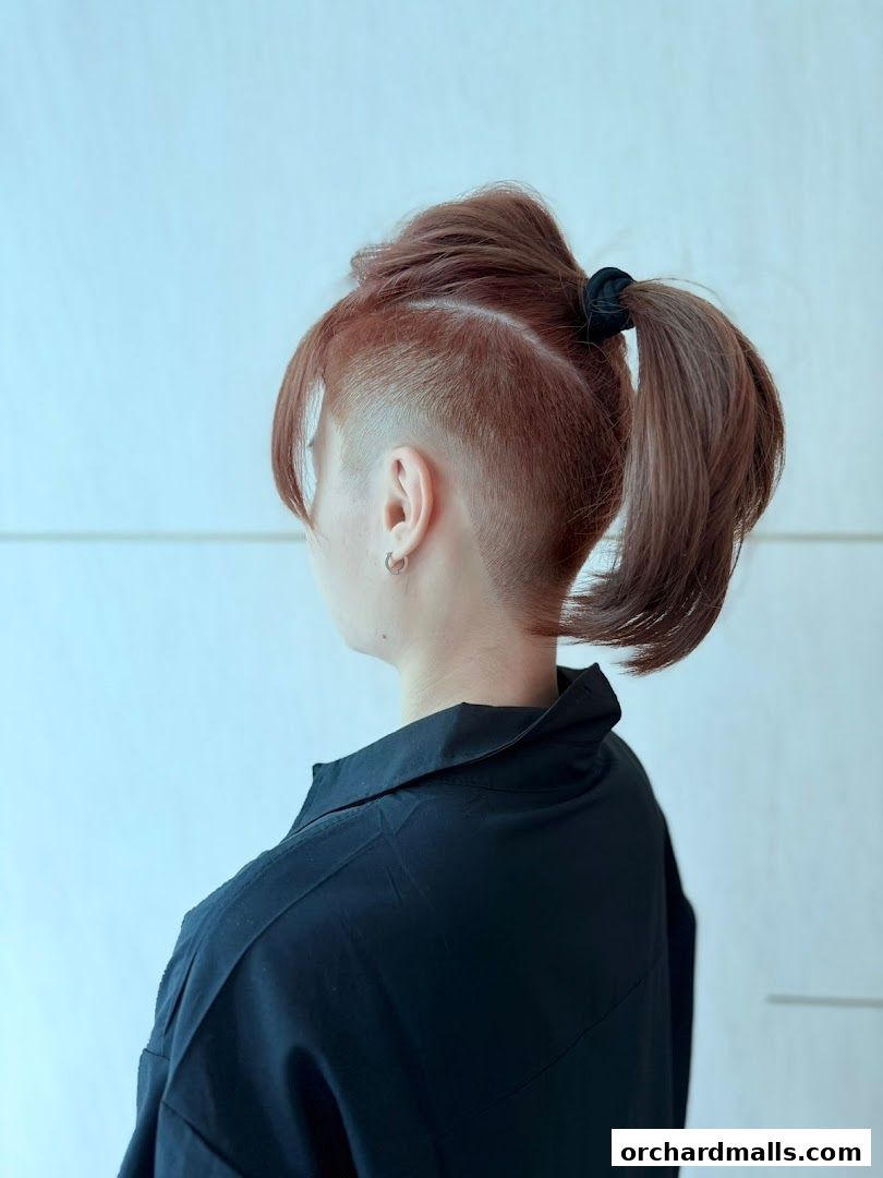A person with a stylish undercut hairstyle and a high ponytail.