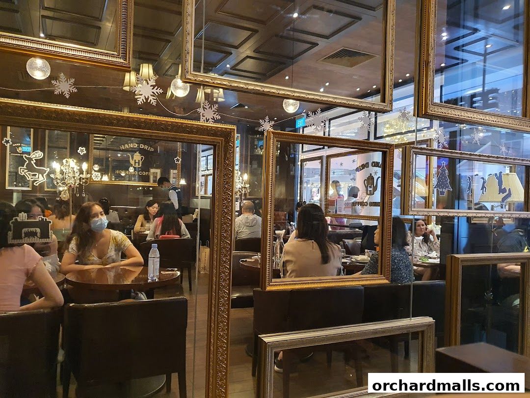 Interior of a cafe with patrons seated at tables, decorated with ornate frames and festive elements.