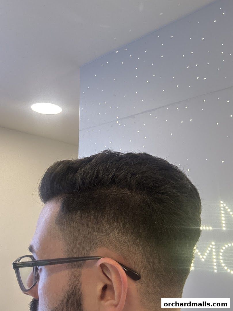 Close-up of a man's haircut with stylish styling and glasses.