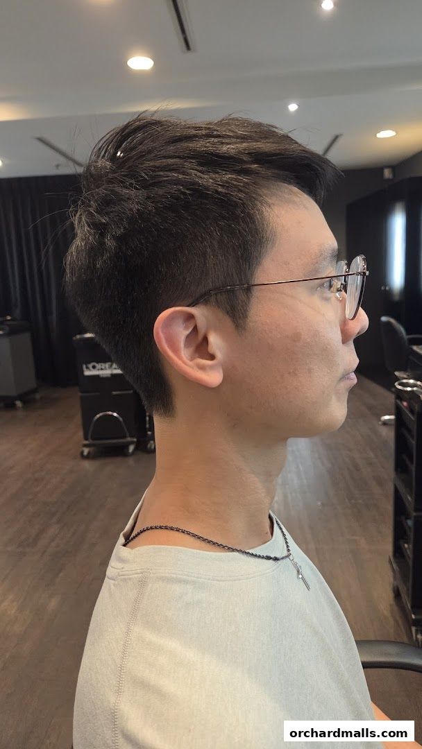 A man with stylishly cut hair and glasses in a salon.
