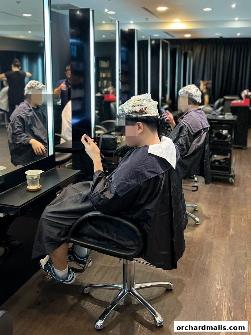 Clients receiving hair treatments in a modern salon with mirrors and styling stations.