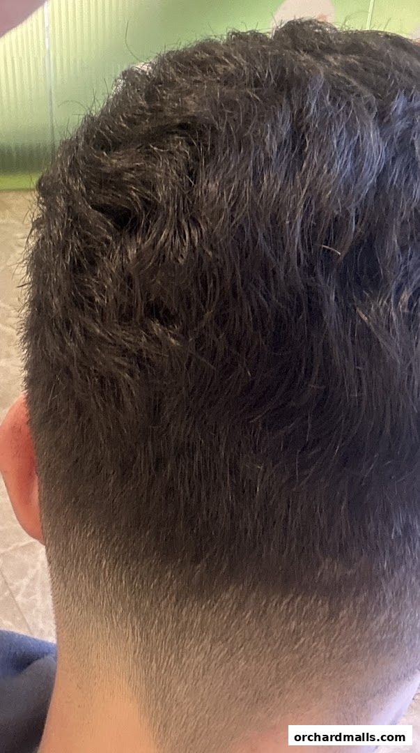 Close-up of a man's dark, textured hair with a faded undercut.