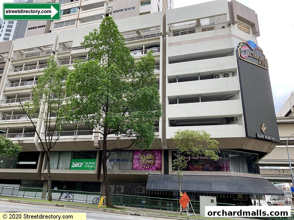 Exterior view of Orchard Towers building with various shops and a large sign.