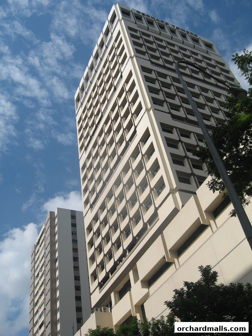 A tall, modern office building with a blue sky and clouds in the background.