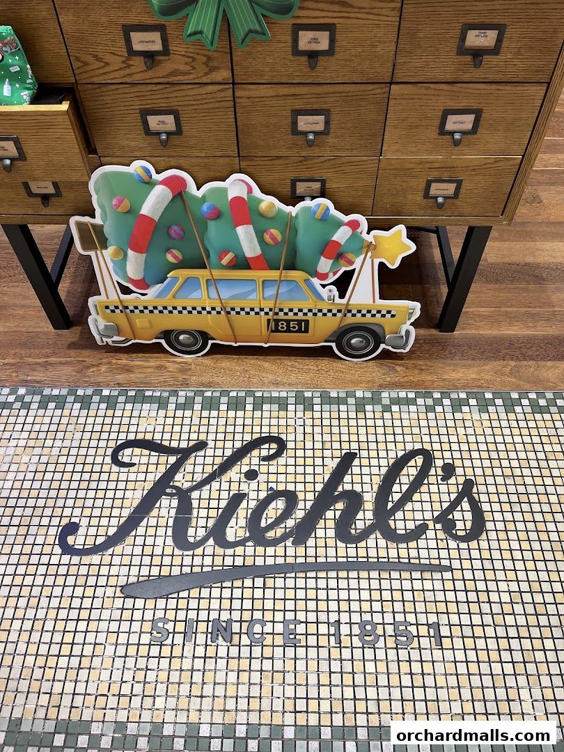 Kiehl's store entrance with a festive holiday display featuring a taxi carrying a Christmas tree.