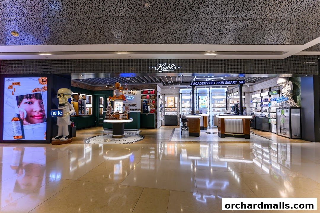 The exterior of a Kiehl's store with a large digital display and product displays inside.