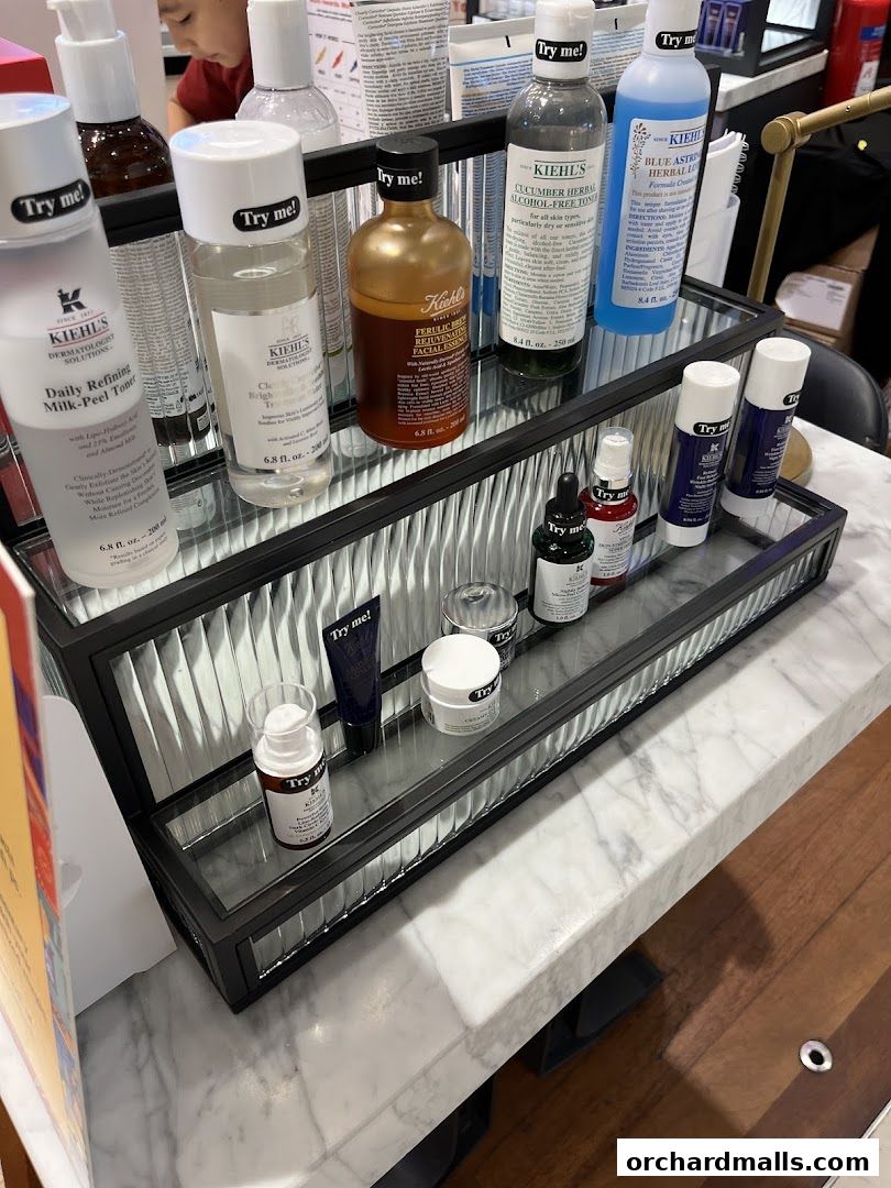 A display of Kiehl's skincare products, including toners, serums, and creams, with 'Try me!' labels.