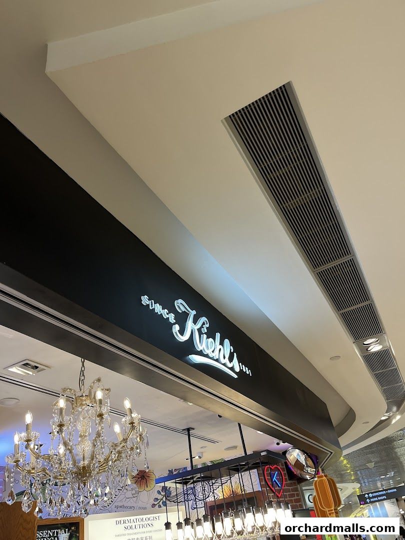 The illuminated Kiehl's sign above a store interior with a chandelier.