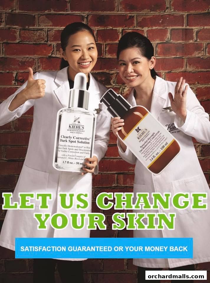 Two women in lab coats hold Kiehl's skincare products, promoting skin transformation.