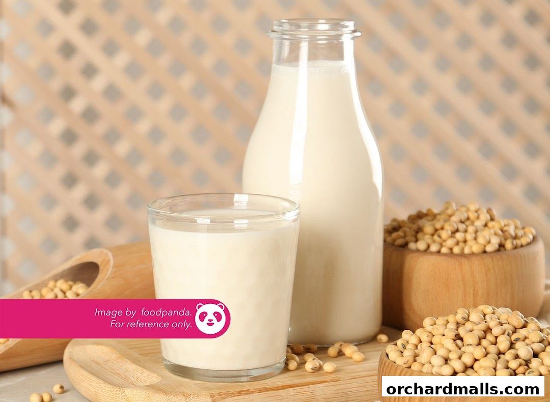 A bottle and glass of soy milk with soybeans in wooden bowls.