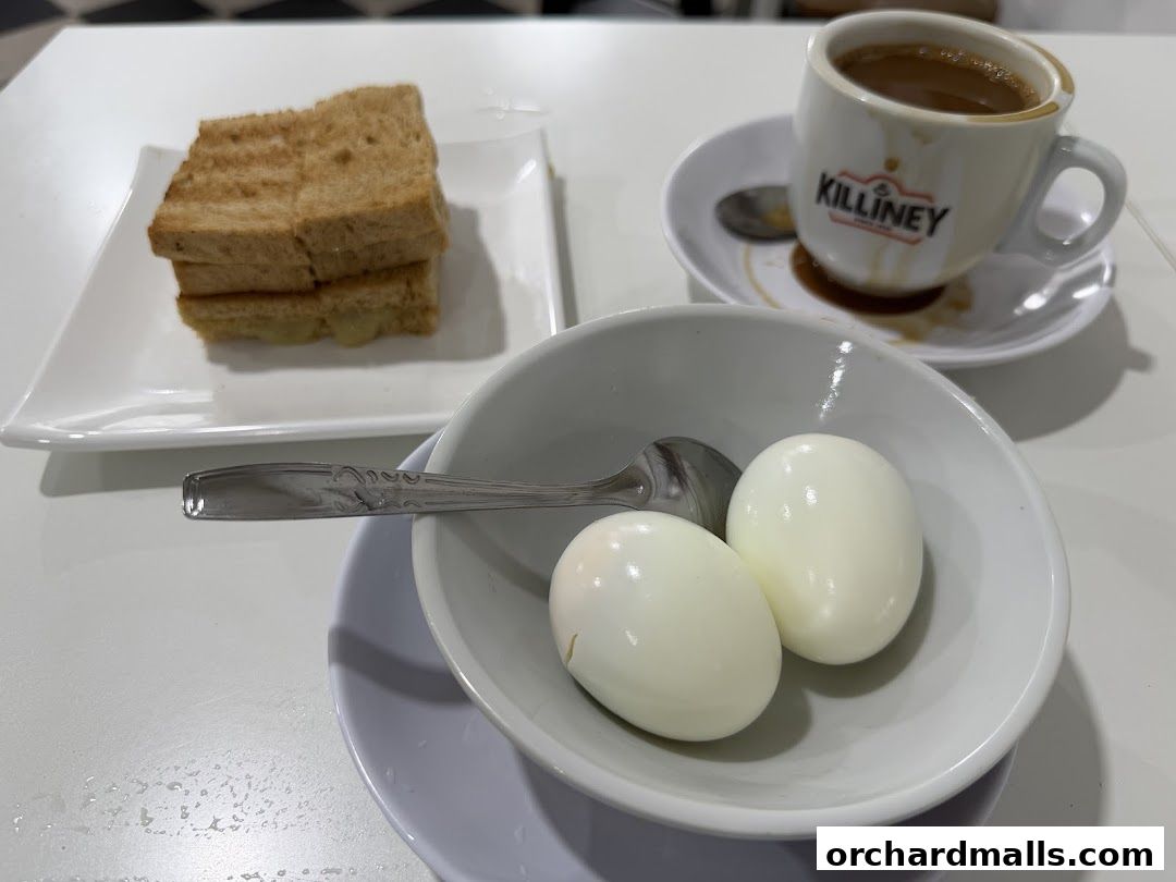 A cup of coffee, toast, and two boiled eggs on a white table.
