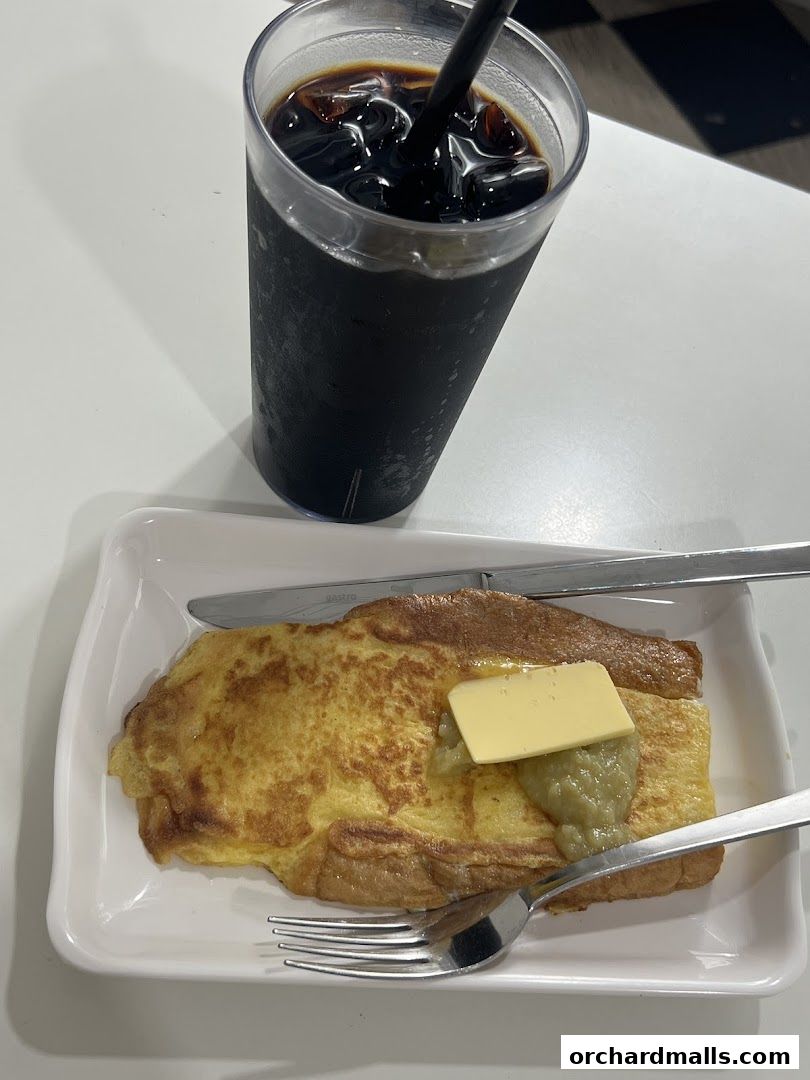 A close-up of French toast with butter and jam, served with iced coffee.