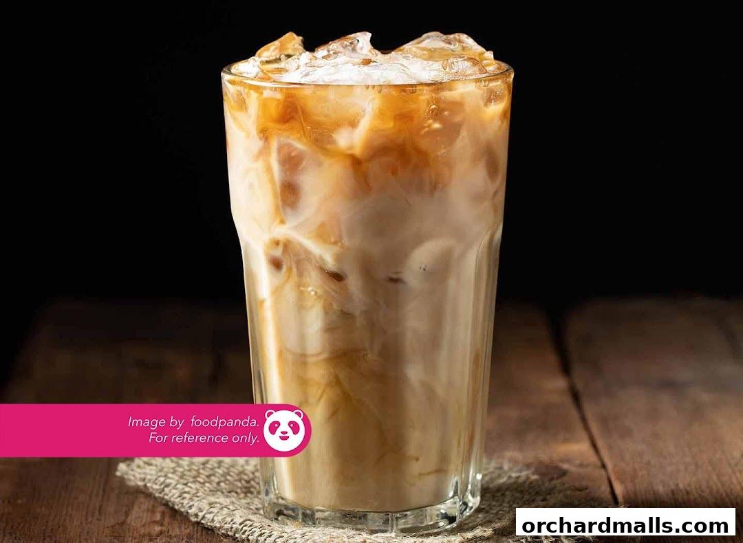 A tall glass filled with iced coffee and cream swirls on a wooden surface.
