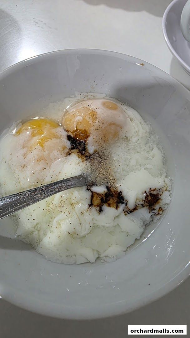 A bowl of soft-boiled eggs with soy sauce and pepper, ready to be eaten.