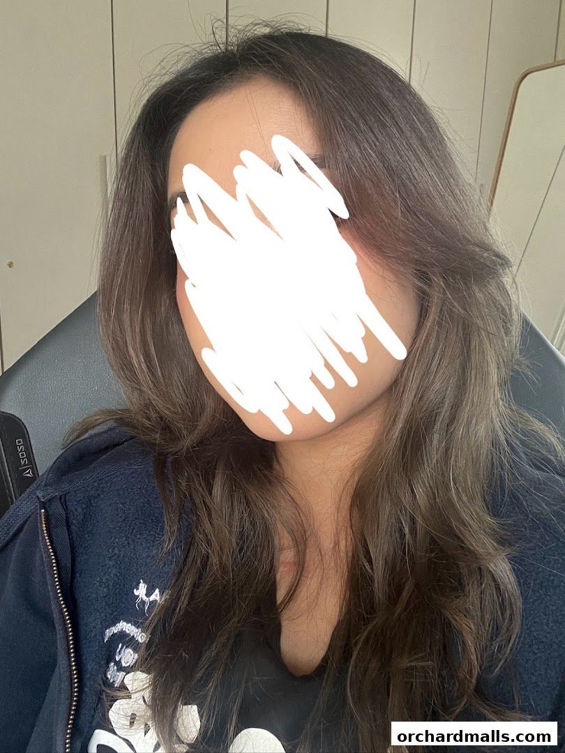 A person with long, wavy brown hair, face obscured by a white scribble.
