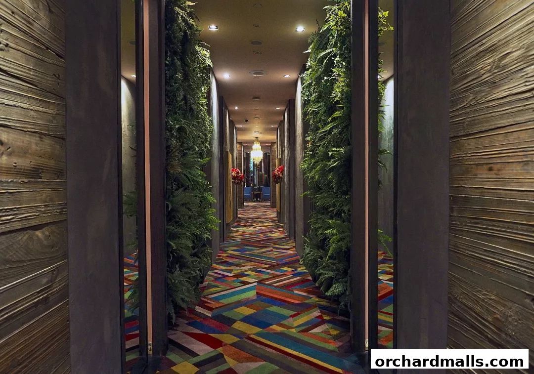 A hallway with lush greenery, a vibrant geometric carpet, and wooden walls.