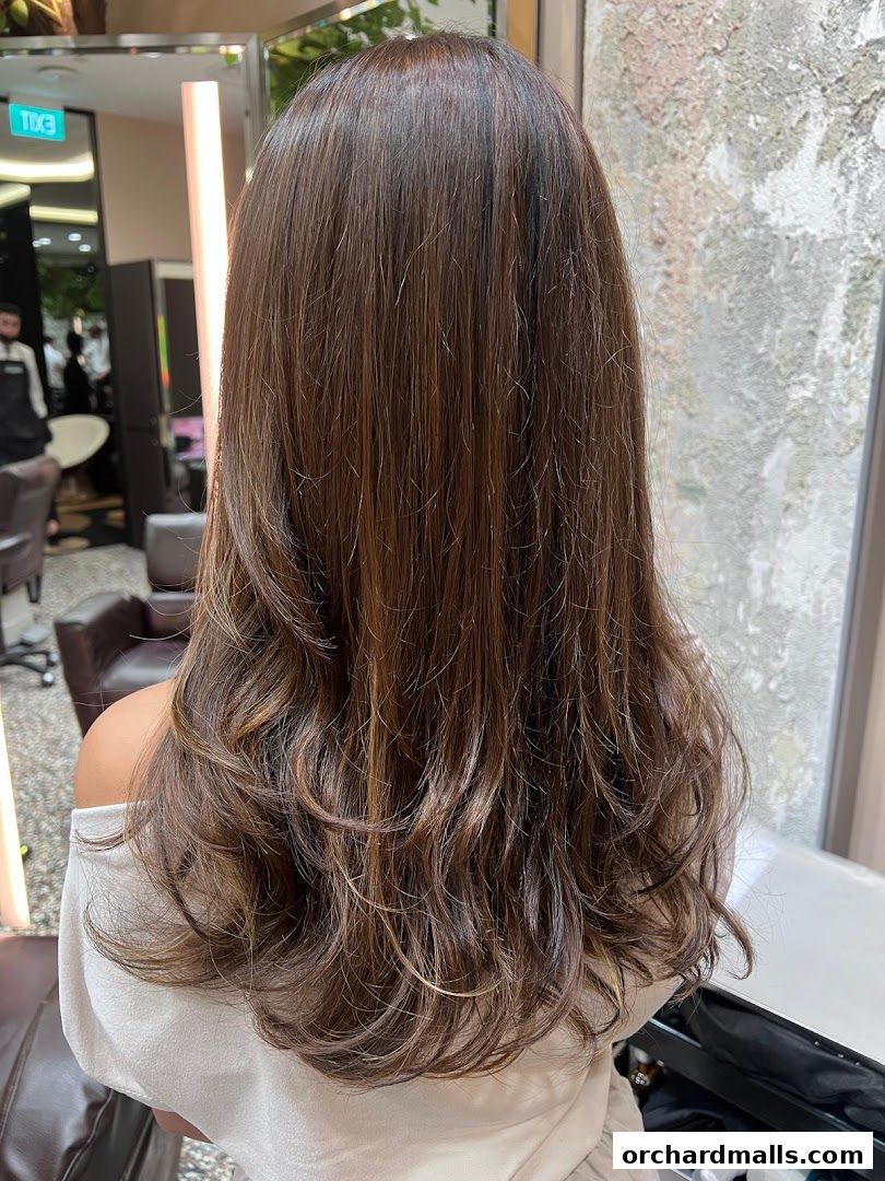 A woman's long, layered brown hair with subtle highlights, styled with waves.