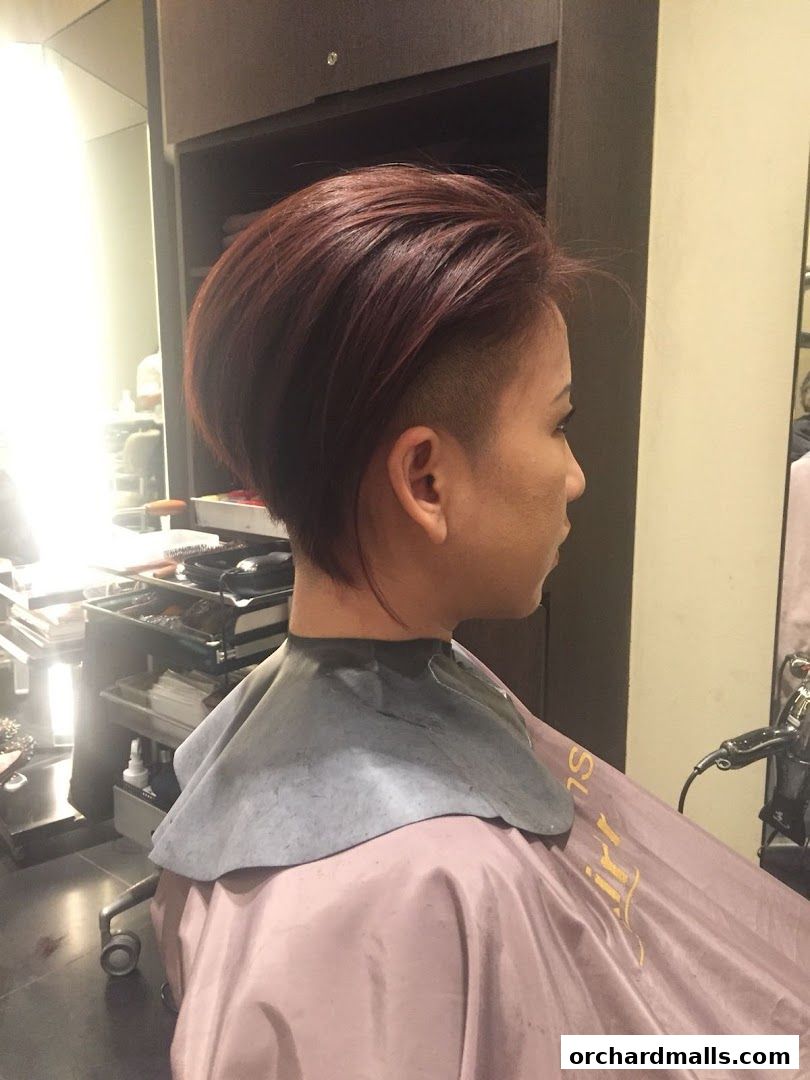 A woman with a stylish undercut hairstyle and auburn hair in a salon.