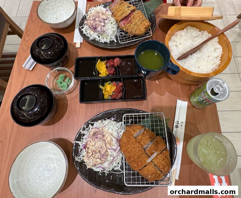 A table setting with two katsu meals, rice, drinks, and condiments.